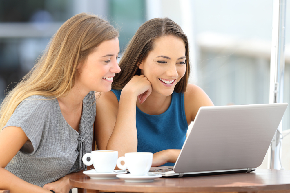 Two women reading a blog on a laptop at a restaurant