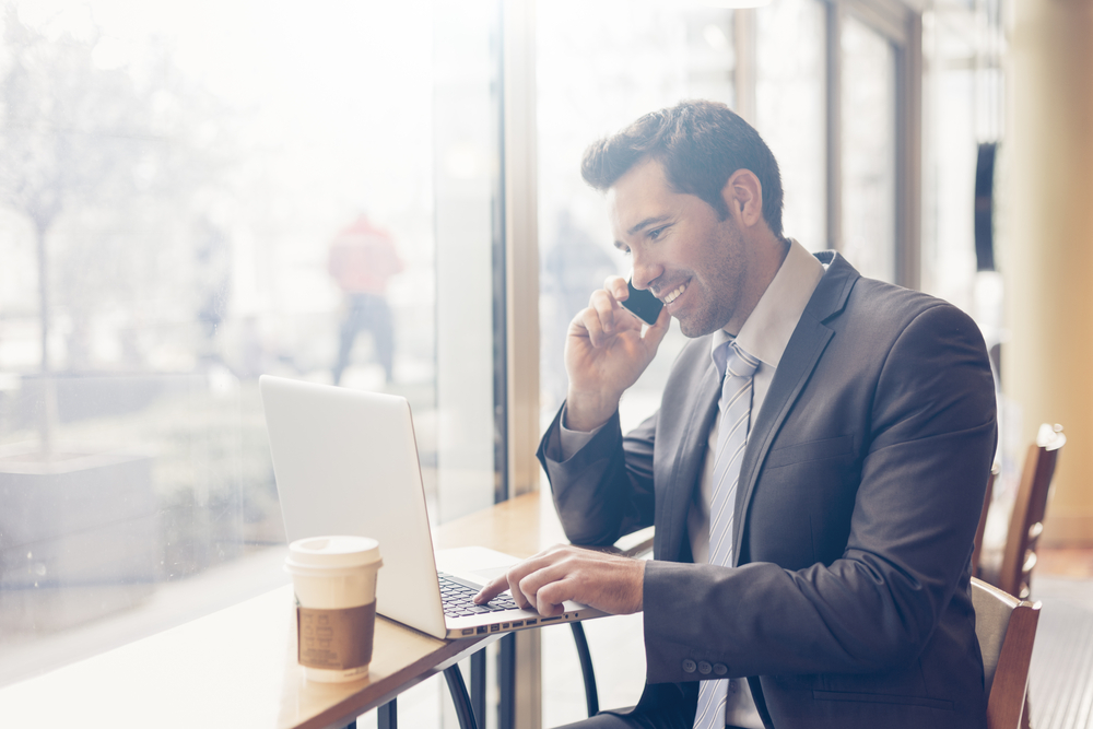 A business man is on his cell phone at a cafe.