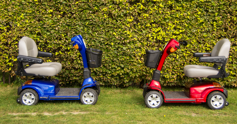 Two mobility scooters on a lawn.